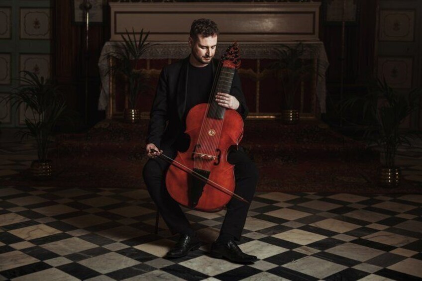 A person playing a cello in a room with a checkered floor and a fireplace. 1