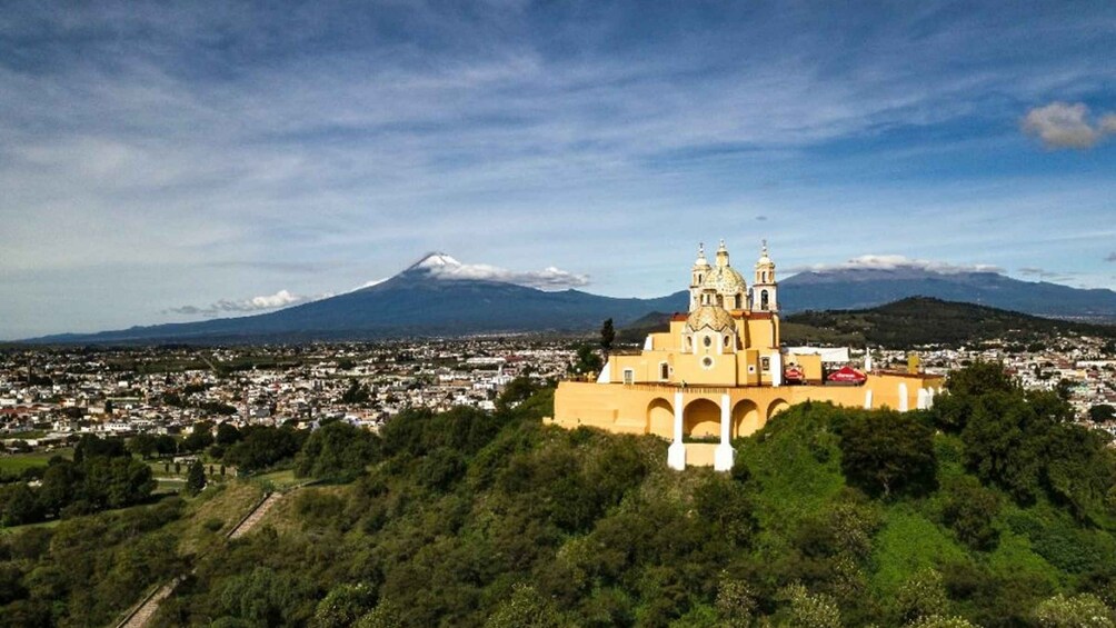 A church with a dome and bell towers, a mountain in the background, and a town below. 2
