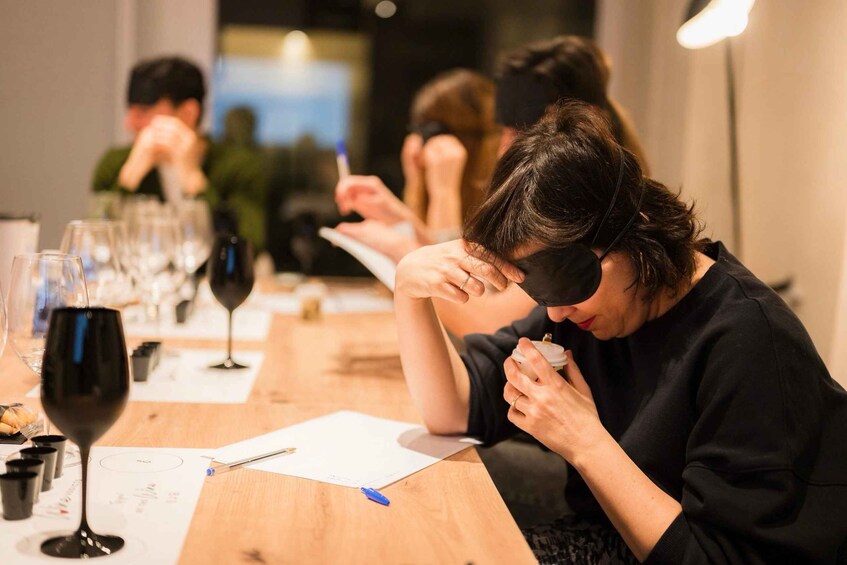 A person writing at a table with wine glasses and papers. 5