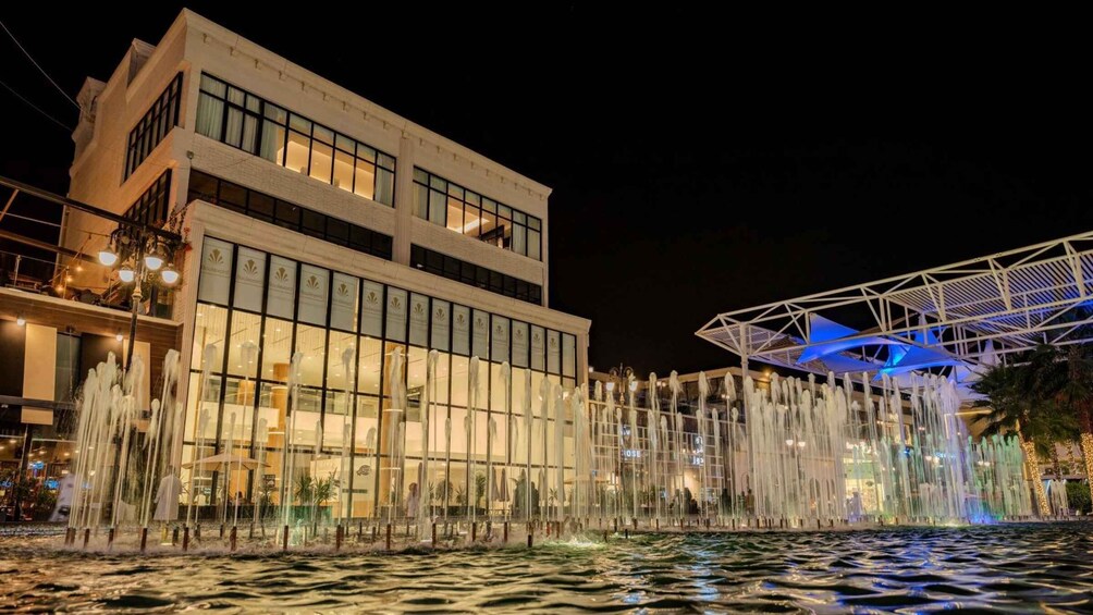 A nighttime view of a building with a water fountain display in front. 5