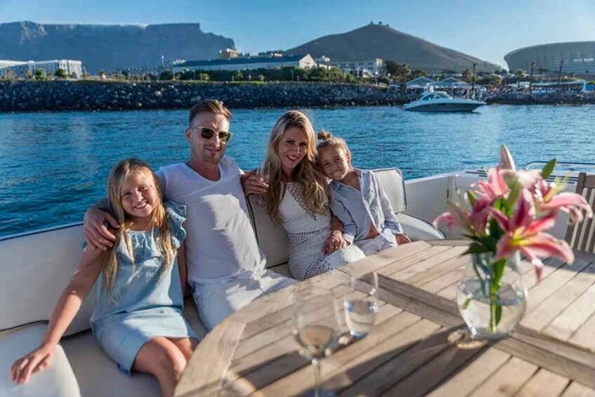 A family on a boat with a view of a coastal city and a large stadium in the background. 5