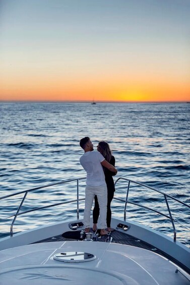 A couple standing on a boat with a sunset in the background. 4