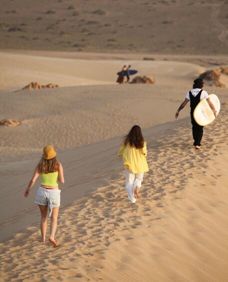 Two people walking on a sandy beach with a surfboard. 2