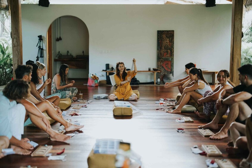 A group of people sitting in a circle on the floor, engaged in a meditation or yoga session. 3