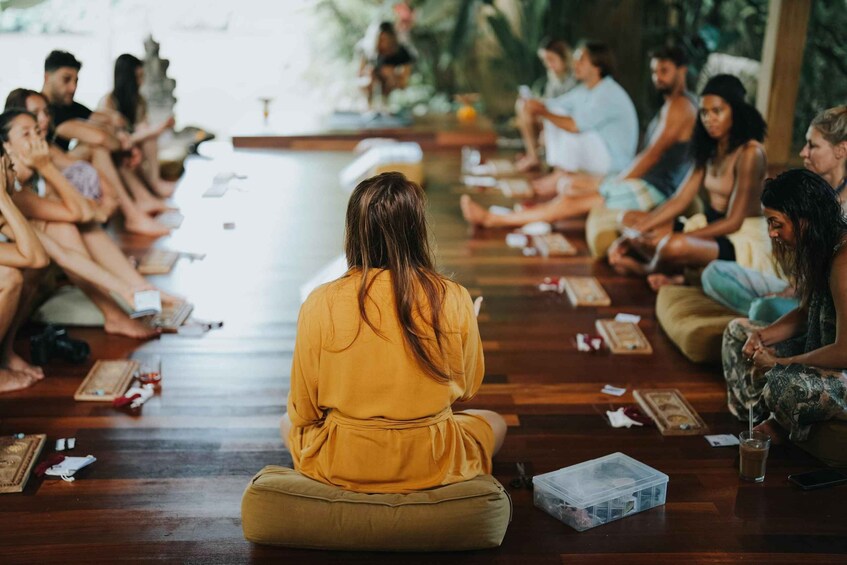 A group of people sitting on the floor in a circle, engaged in a meditation or yoga session. 5