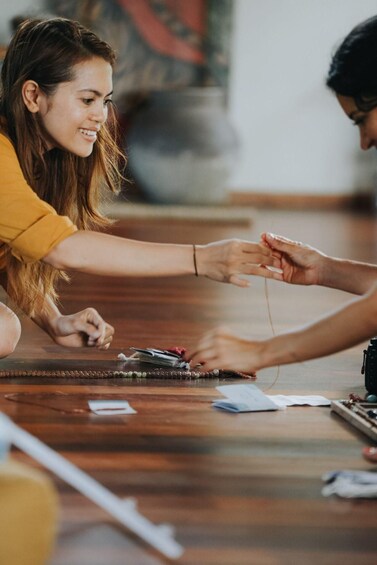 Two people sitting on the floor, one handing over a card to the other. 2