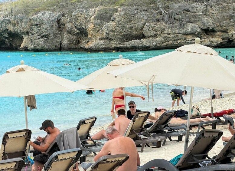 A beach with lounge chairs and umbrellas, people swimming and sunbathing. 3