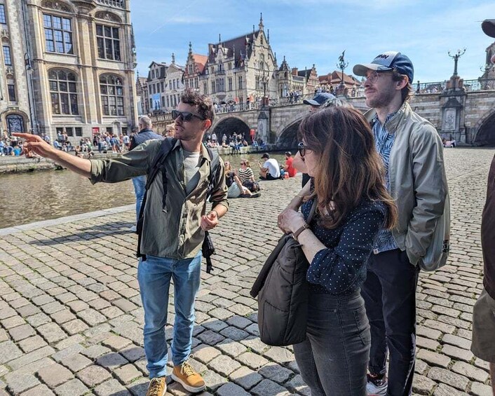 A group of people standing on a cobblestone bridge with historic buildings in the background. 4