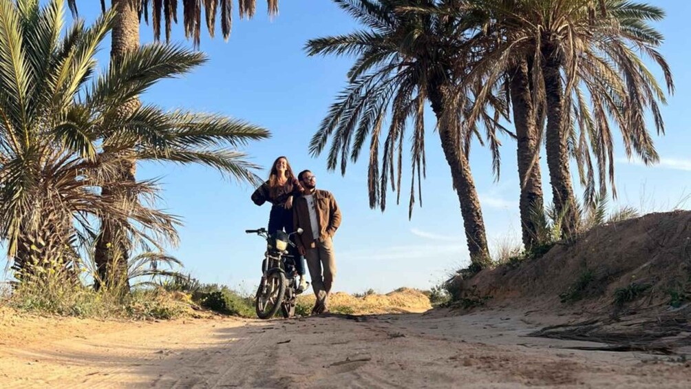 A dirt road flanked by palm trees under a clear sky. 3
