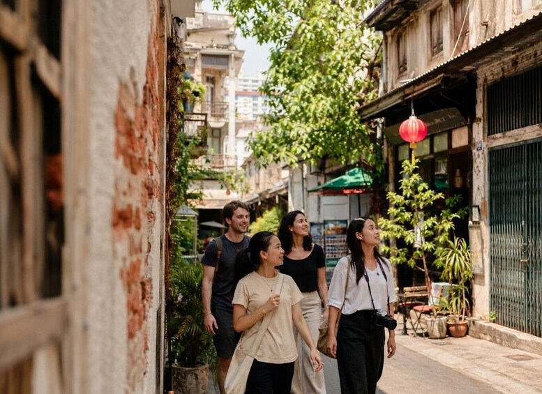 A narrow alley with buildings, a red lantern, and potted plants. 5