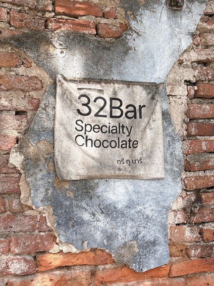 A brick wall with a sign reading '32Bar Specialty Chocolate.' 2