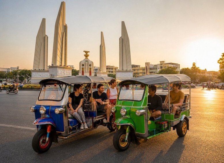 Two tuk-tuks with passengers, a monument with four tall spires, and a sunset in the background. 1