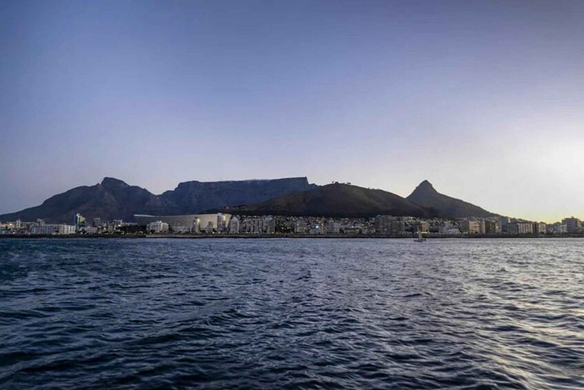 A coastal cityscape with mountains in the background and a calm sea in the foreground. 2