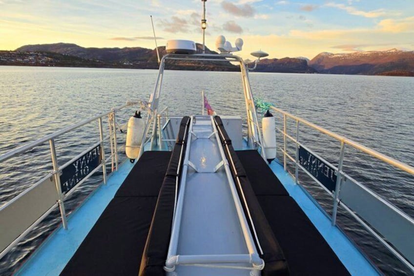 A boat deck with a wakeboard ramp, railings, and a view of a calm lake with distant mountains. 2