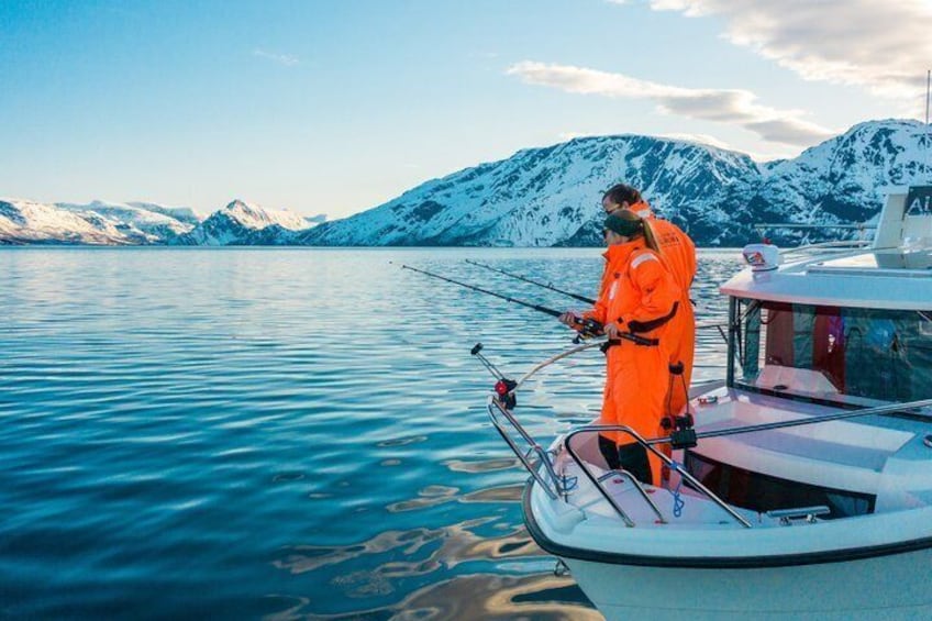 A person fishing on a boat with snow-capped mountains in the background. 5