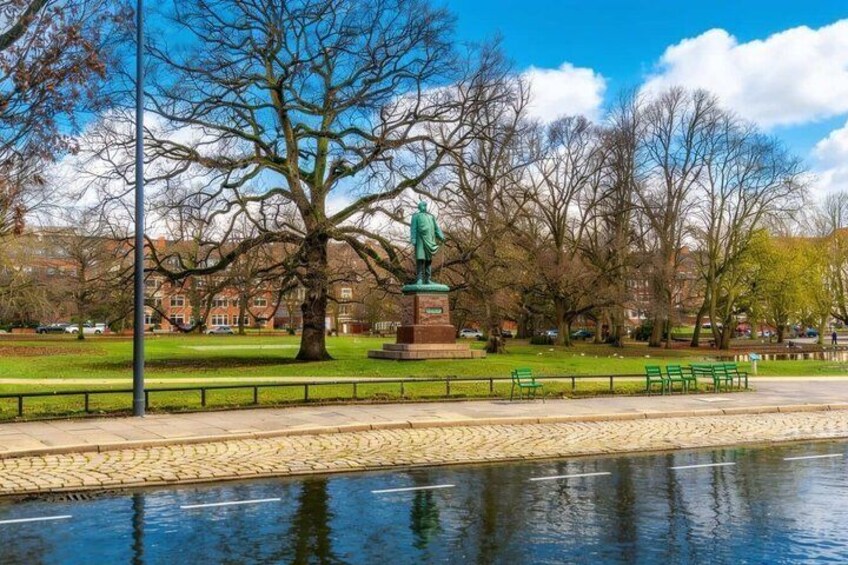 A park with a statue, a body of water, and a row of benches. 2