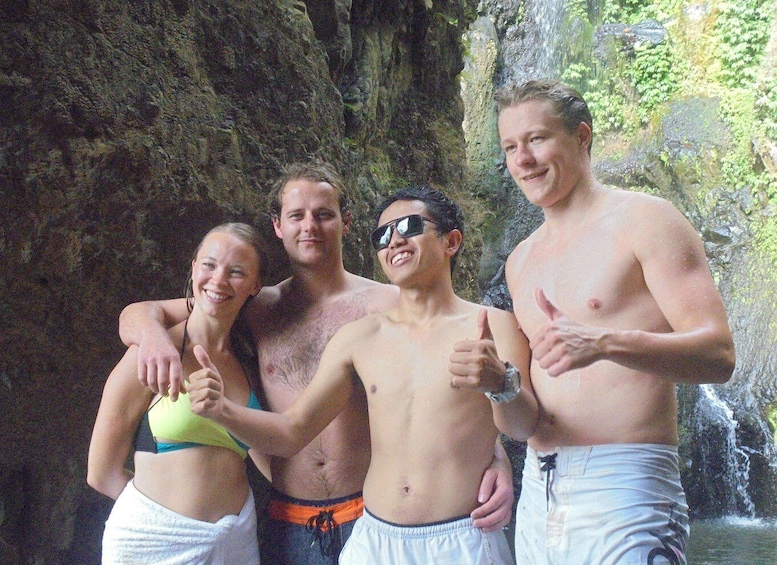 A group of people posing in front of a rocky waterfall. 5