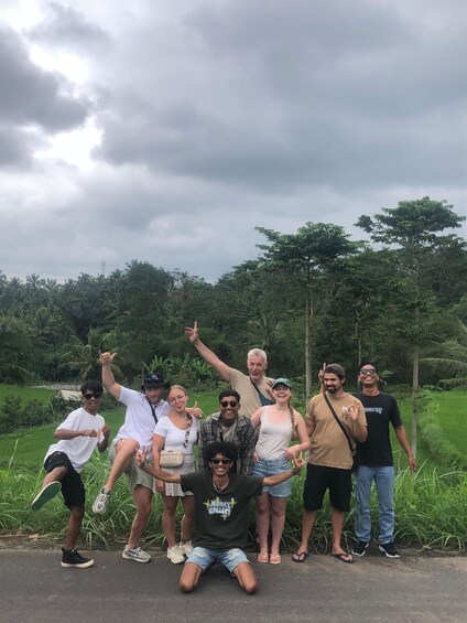A group of people posing outdoors with a lush green landscape and trees in the background. 2
