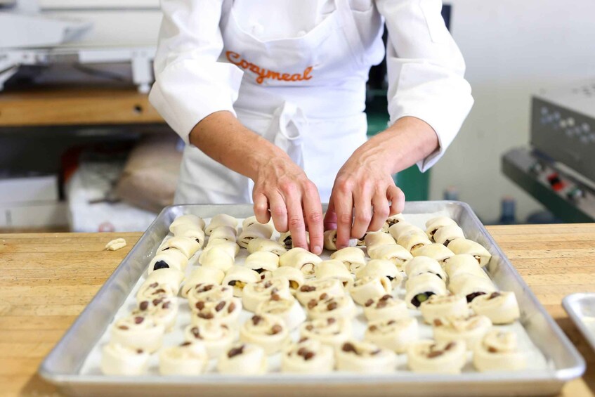 A person arranging rolled dough with nuts on a baking tray in a kitchen. 5