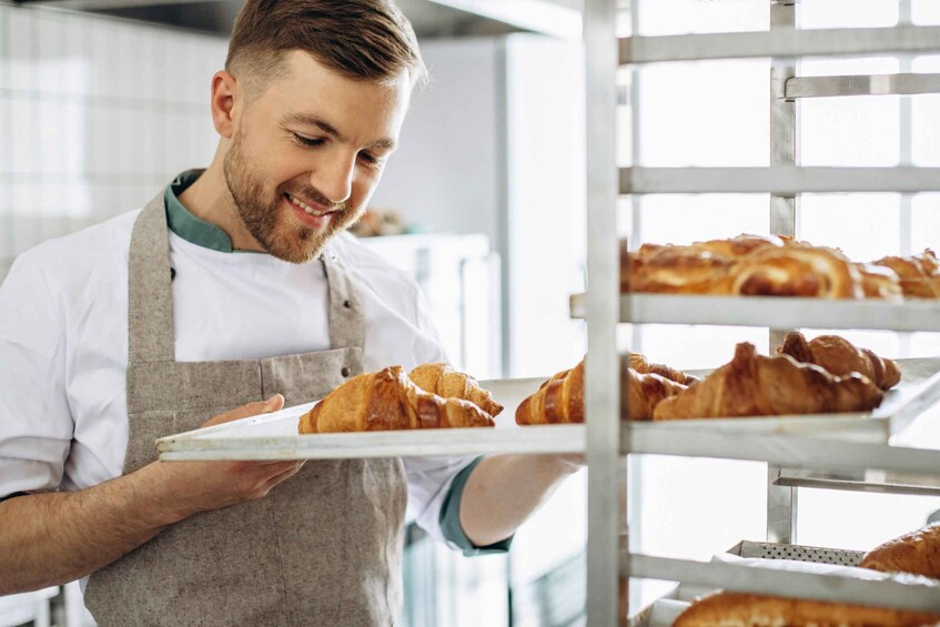 A person holding a tray with croissants in a bakery. 2