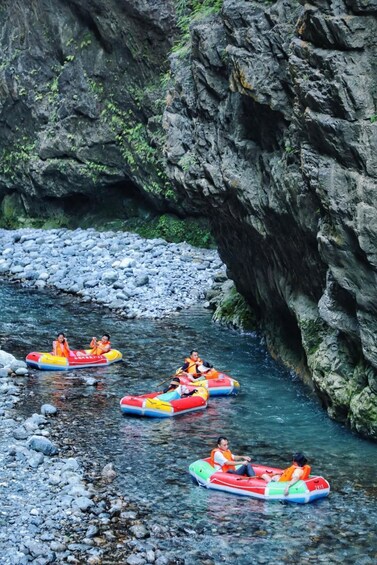 People rafting on a river surrounded by rocky cliffs. 3