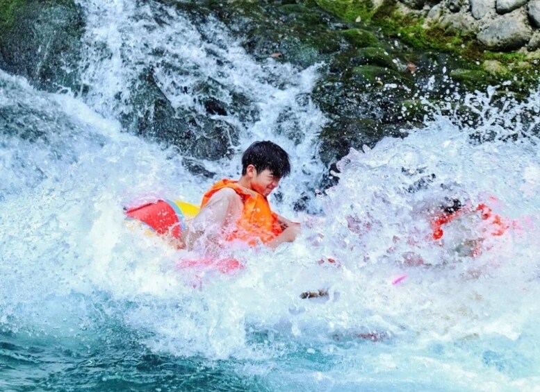 A person in a life jacket riding a wave. 5