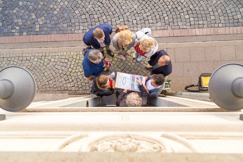 A group of people gathered around a stone fountain, examining a map. 2