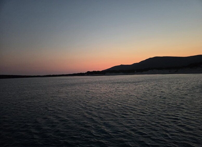 A calm body of water with a mountain silhouette in the background during sunset. 5