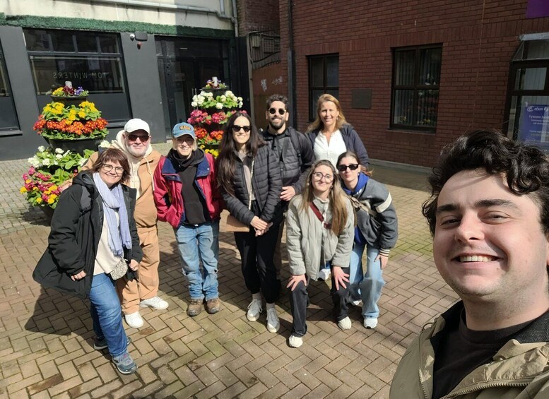 A group of people standing in front of a building with a brick facade and flower arrangements. 1
