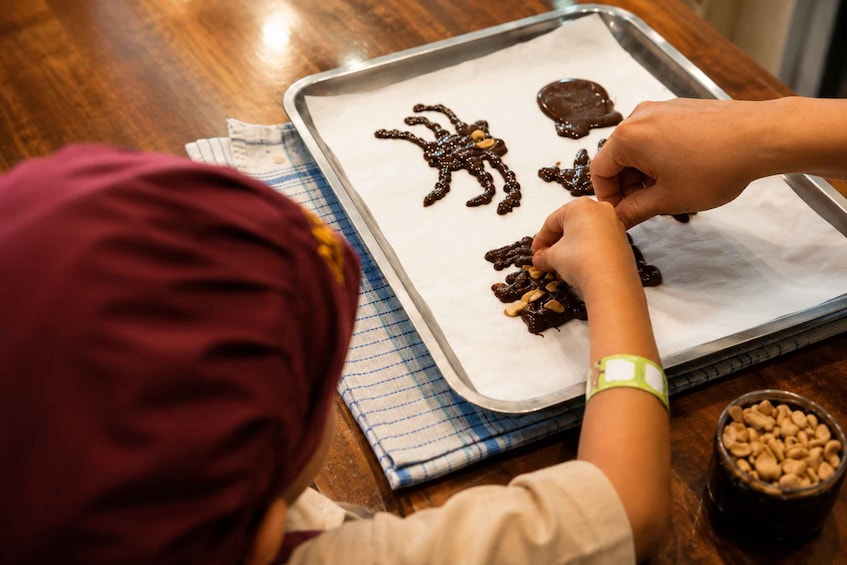 A person shaping chocolate on parchment paper with nuts. 2