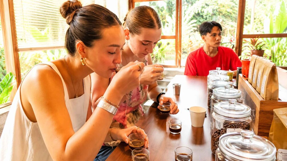Three people at a table with coffee and sugar containers. 1