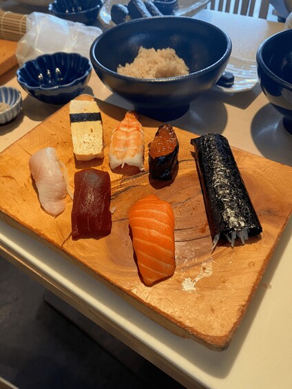 A wooden board with various types of sushi, including salmon and tuna, on a table. 2