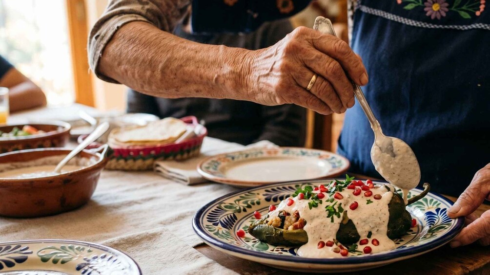 An elderly person serving a dish with a creamy sauce and pomegranate seeds on a decorative plate. 4