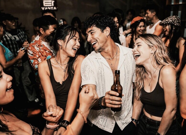 A crowded indoor social event with people holding drinks and engaging in conversation. 1