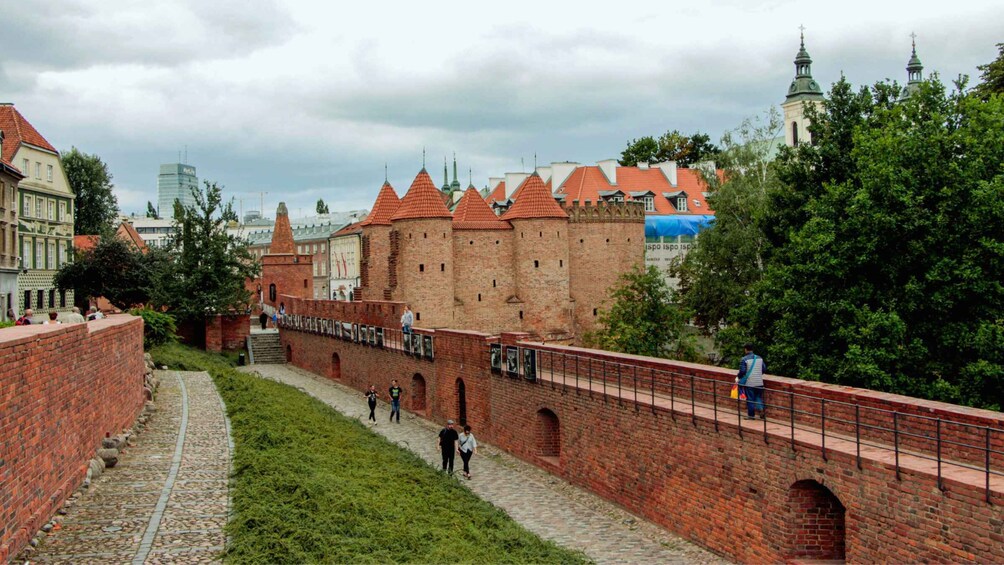 A historic brick wall with a bridge, a castle in the background, and a modern building with a glass facade. 5