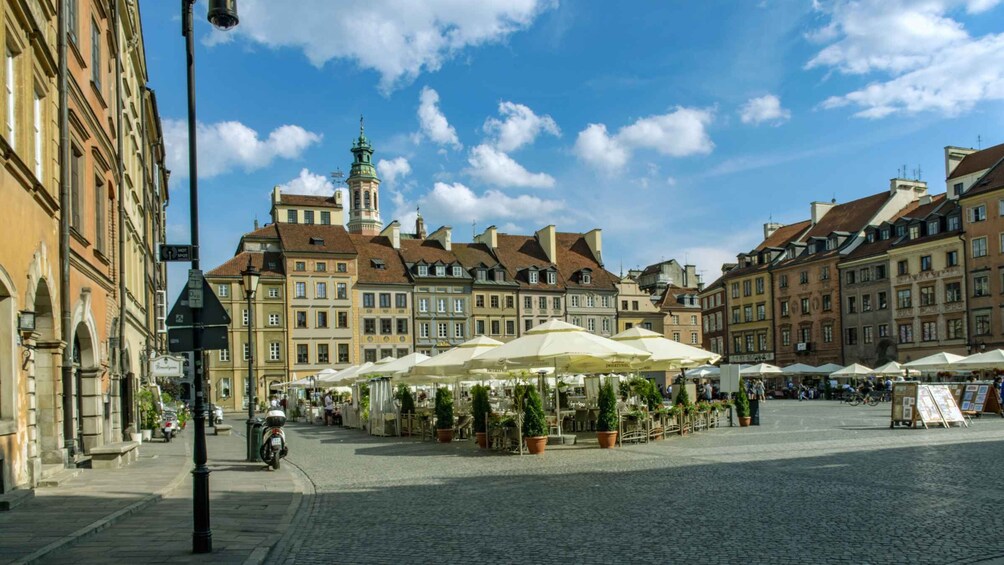 A cobblestone square with historic buildings, a church tower, and outdoor cafes. 2