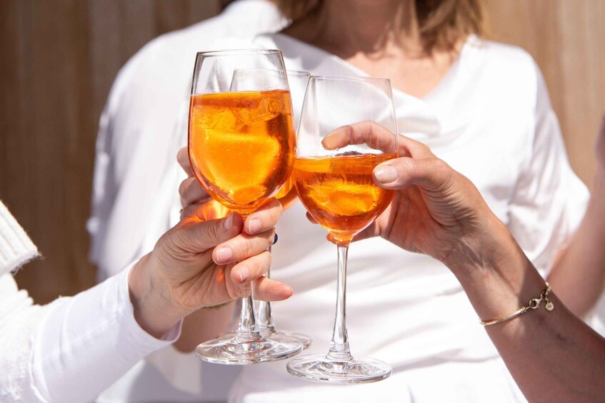 Two people holding glasses of amber-colored drink with orange slices. 1