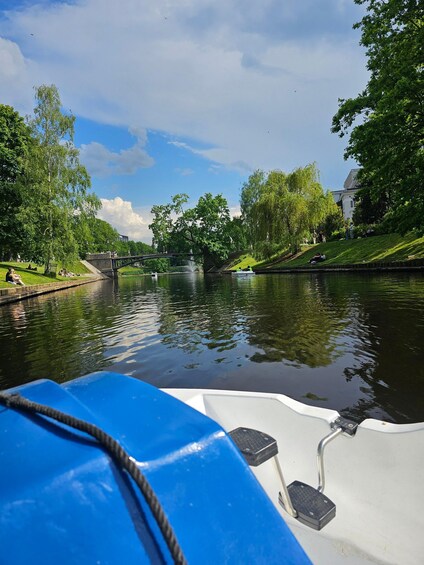 A calm river with a bridge, lush greenery, and a boat in the foreground. 3