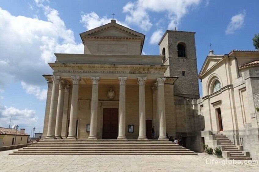 A classical building with columns, a bell tower, and a staircase leading to the entrance. 4