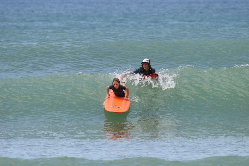 Two people on a surfboard in the ocean. 3