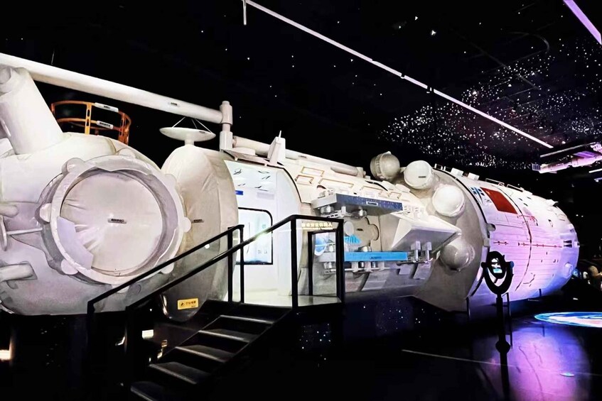 A space shuttle on display with a glass walkway and a starry background. 2