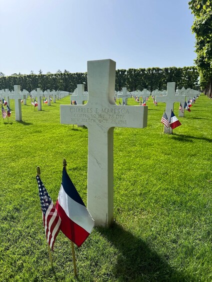 A cemetery with white crosses and flags, including American and French flags. 4