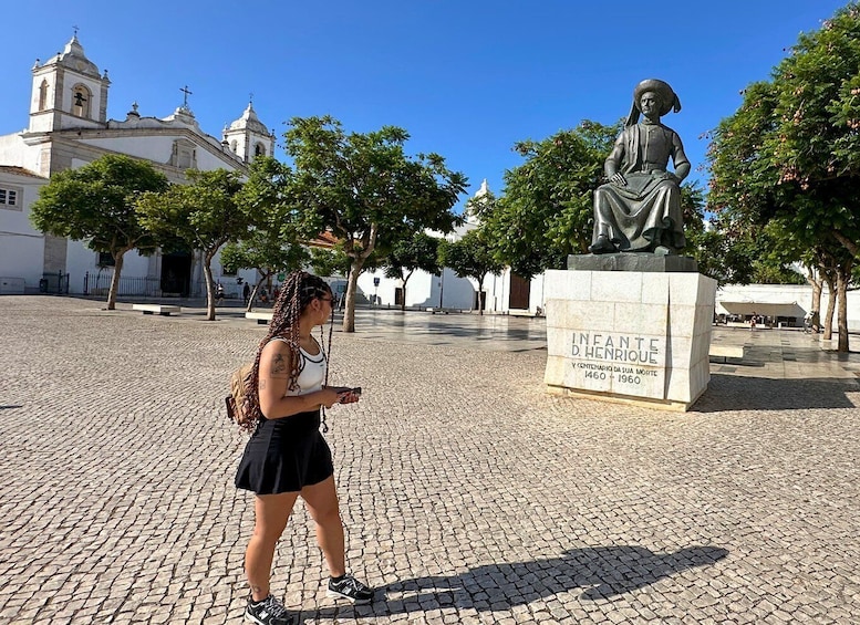 A statue of a historical figure in a public square with cobblestone pavement and a church in the background. 2