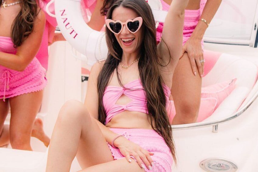 A person in a pink swimsuit sitting on a boat with a heart-shaped object. 4