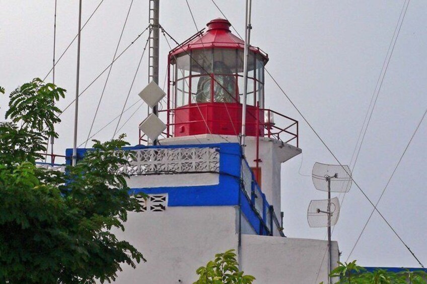 A lighthouse with a red top, white and blue base, and a white fan on the side. 2