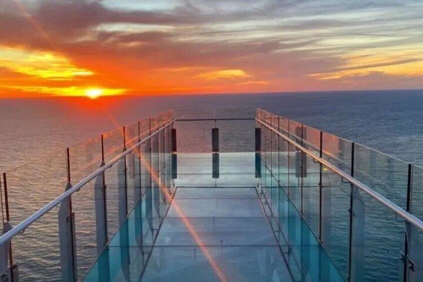 A glass-bottomed walkway overlooking the ocean at sunset. 3
