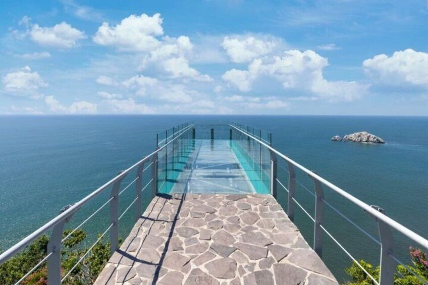 A glass-bottomed infinity pool extending over the ocean, with a stone deck and metal railing. 5