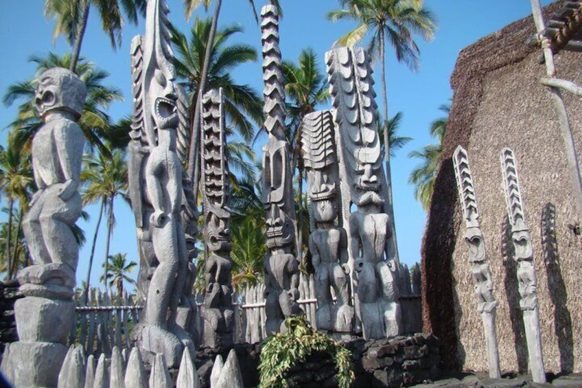 A collection of stone sculptures and tiki figures, surrounded by palm trees. 5