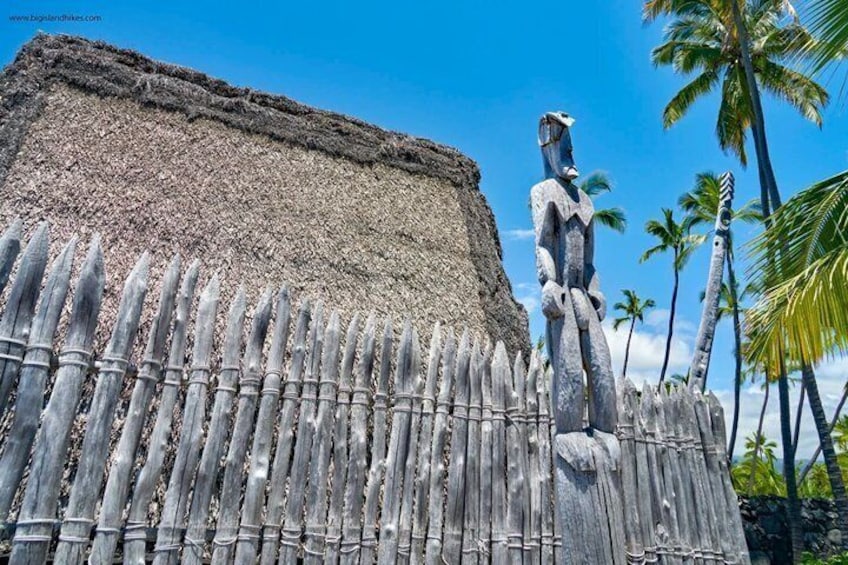 A thatched-roof structure with a bamboo fence and a stone statue. 4