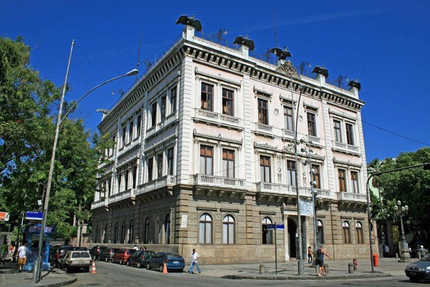 A multi-story building with ornate architectural details, including a balcony and decorative elements on the roof. 5